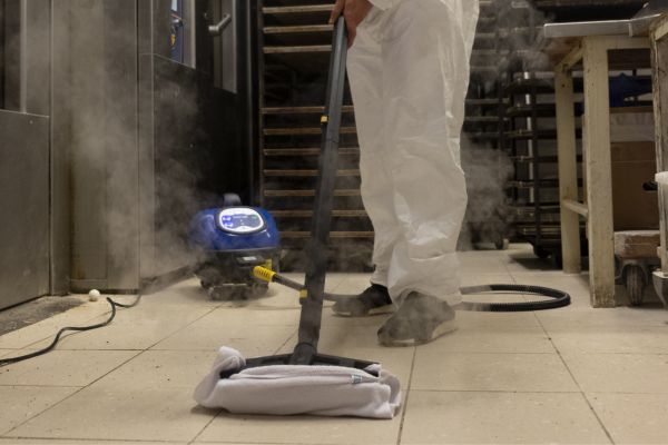 Steam cleaning greasy floors inside a kitchen